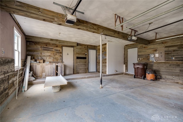 garage with electric panel, wooden walls, and a garage door opener