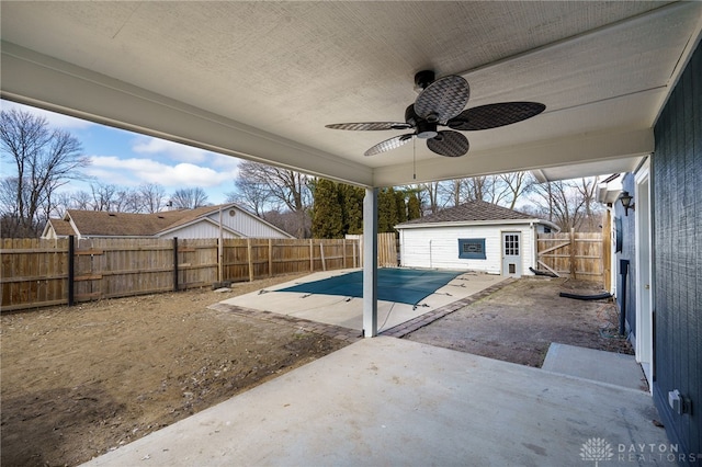 view of pool featuring a patio area, a fenced backyard, a ceiling fan, and an outbuilding