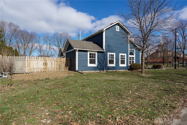 view of side of home with fence and a lawn