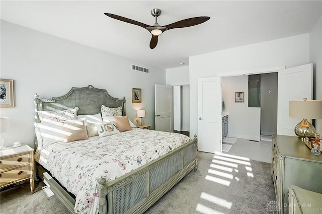 bedroom with connected bathroom, light colored carpet, and ceiling fan