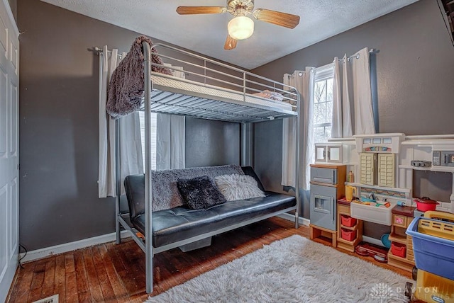 bedroom with ceiling fan, hardwood / wood-style floors, and a textured ceiling