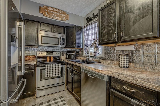 kitchen with dark brown cabinetry, sink, a textured ceiling, light tile patterned floors, and stainless steel appliances