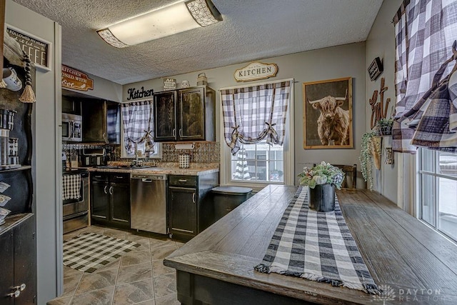 kitchen with dark brown cabinetry, sink, a textured ceiling, and appliances with stainless steel finishes