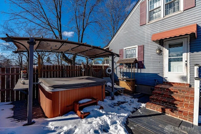 snow covered deck with a hot tub and a pergola