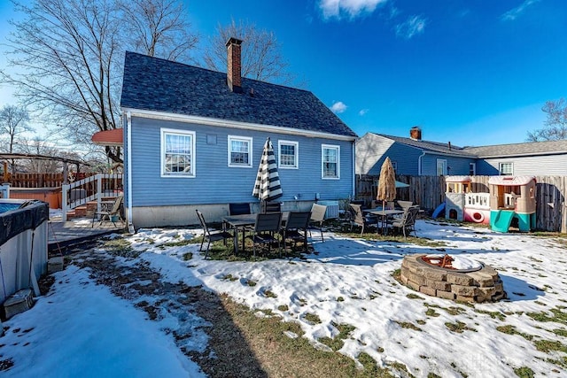 snow covered back of property with an outdoor fire pit