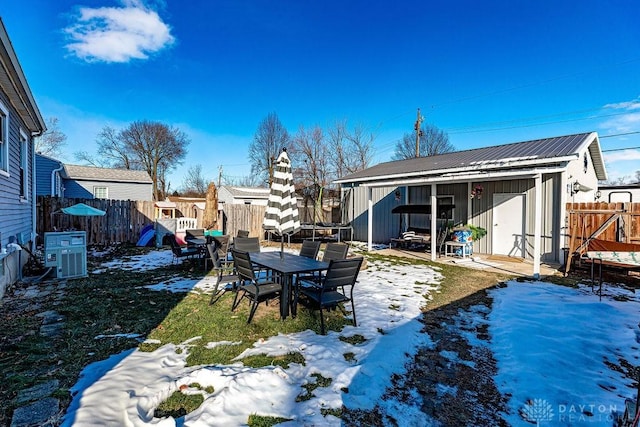 yard covered in snow with an outdoor structure and central air condition unit