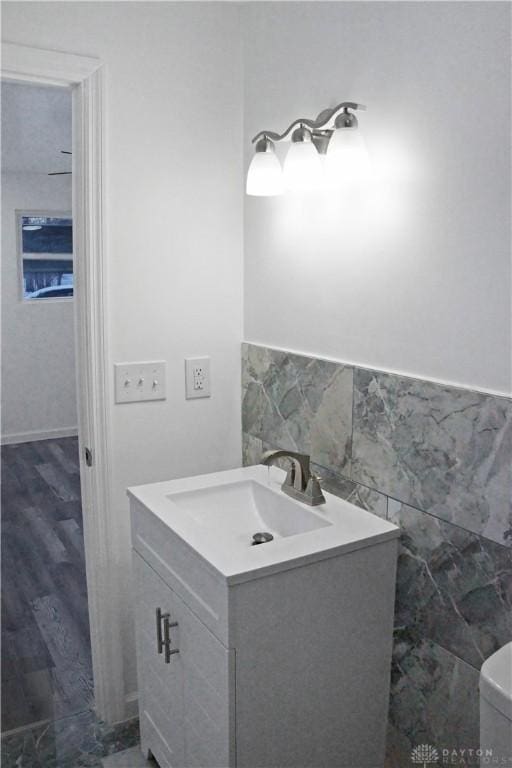 bathroom with vanity, toilet, and tile walls