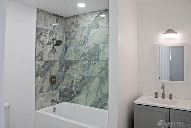 full bathroom featuring tiled shower / bath combo, vanity, and toilet