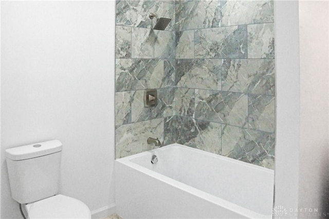 bathroom featuring tiled shower / bath combo and toilet