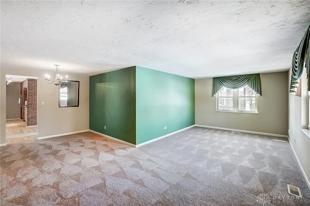 carpeted empty room featuring plenty of natural light, a chandelier, and a textured ceiling