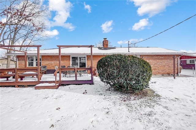 snow covered rear of property with a deck