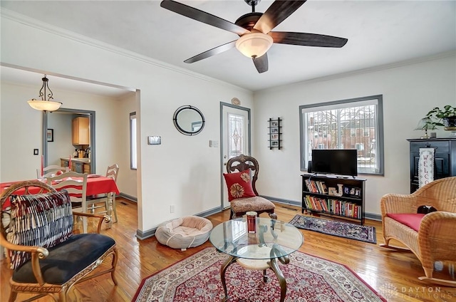 living room featuring light hardwood / wood-style flooring, ornamental molding, and ceiling fan