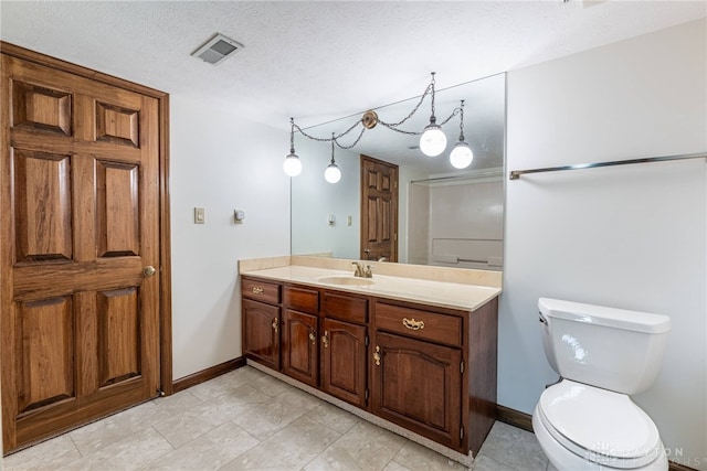 bathroom with vanity, a textured ceiling, and toilet