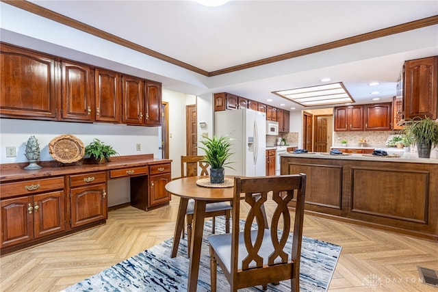 dining room featuring light parquet flooring, ornamental molding, and built in desk