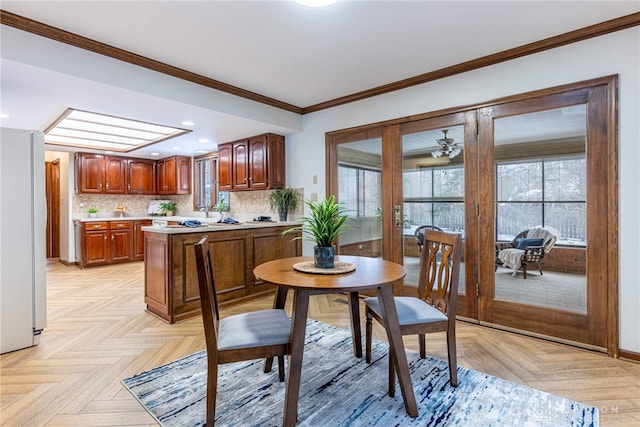 dining space with ornamental molding and light parquet flooring