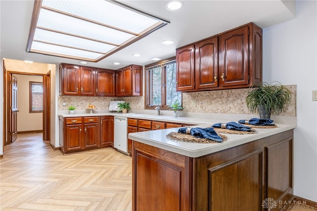 kitchen featuring tasteful backsplash, light parquet floors, kitchen peninsula, and dishwasher