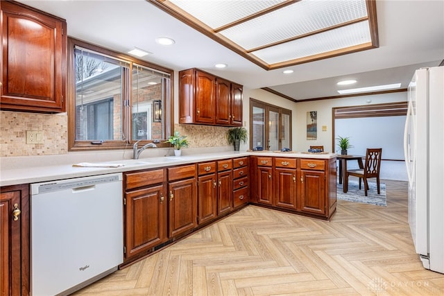 kitchen featuring sink, backsplash, light parquet floors, kitchen peninsula, and white appliances