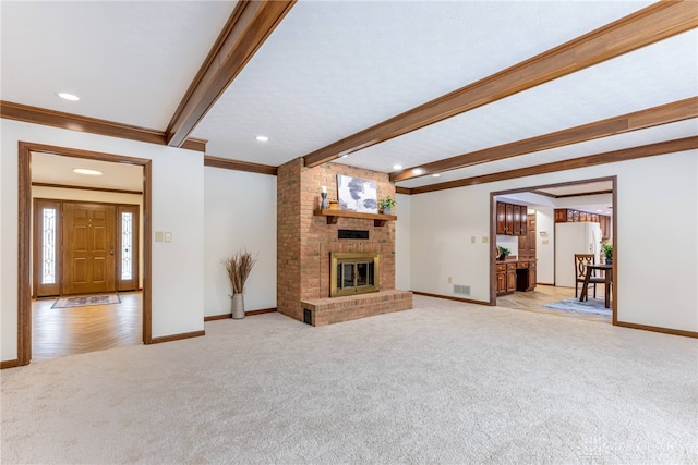 unfurnished living room with beamed ceiling, light colored carpet, and a fireplace