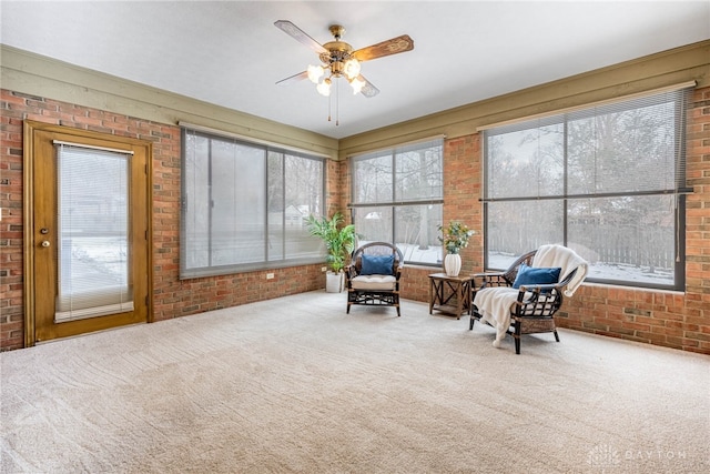 sitting room featuring brick wall, carpet floors, and a wealth of natural light