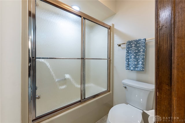 bathroom with toilet and shower / bath combination with glass door