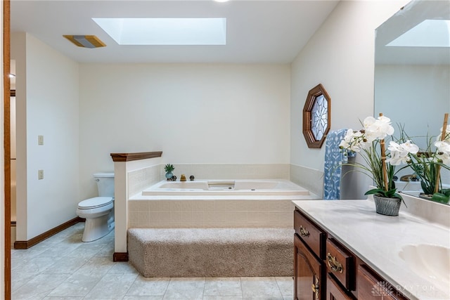 bathroom with a relaxing tiled tub, vanity, toilet, and a skylight