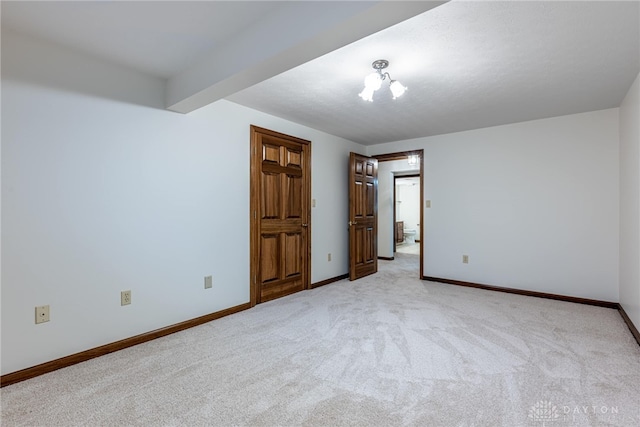 unfurnished bedroom featuring an inviting chandelier, beam ceiling, and light colored carpet