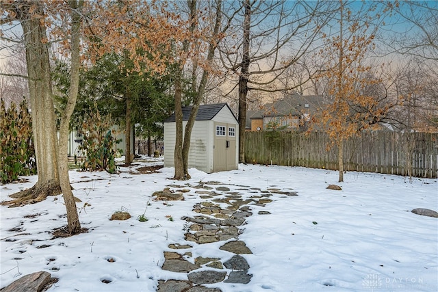 snowy yard featuring a shed