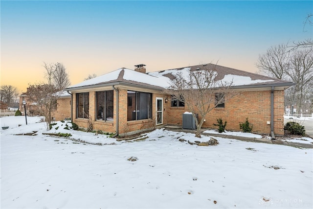 snow covered property with central AC and a sunroom