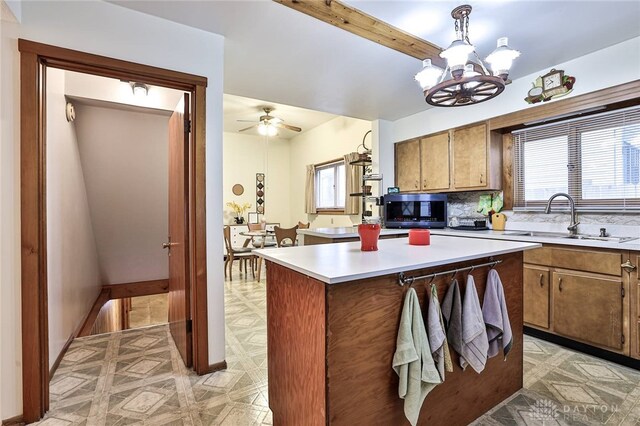 kitchen featuring sink, a center island, hanging light fixtures, ceiling fan with notable chandelier, and decorative backsplash