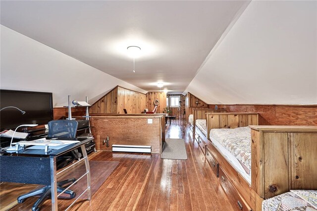 bedroom with baseboard heating, wooden walls, dark hardwood / wood-style flooring, and vaulted ceiling