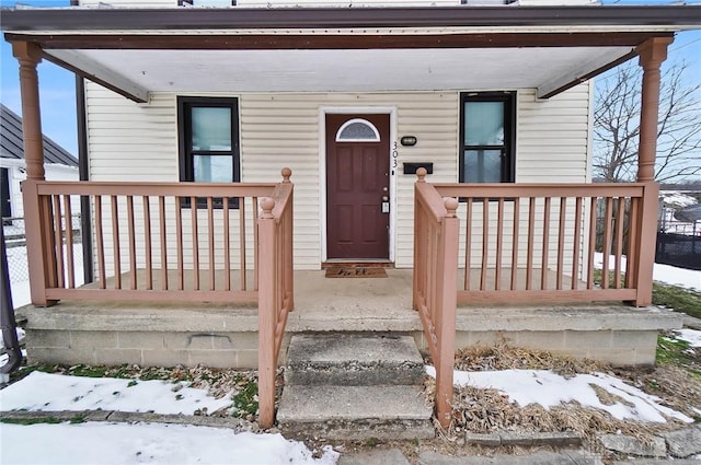 snow covered property entrance with a porch