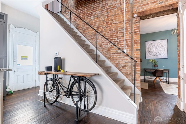 stairway featuring hardwood / wood-style floors and brick wall