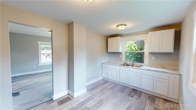 kitchen featuring white cabinetry, sink, and light hardwood / wood-style floors