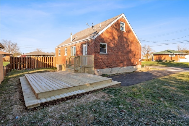 rear view of property featuring a wooden deck and a lawn