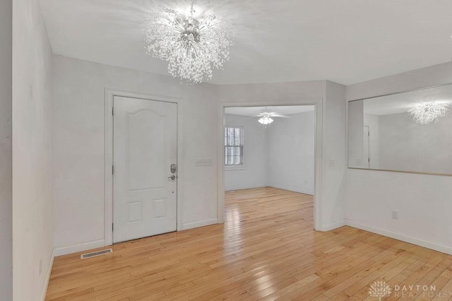 foyer featuring ceiling fan with notable chandelier and light hardwood / wood-style floors