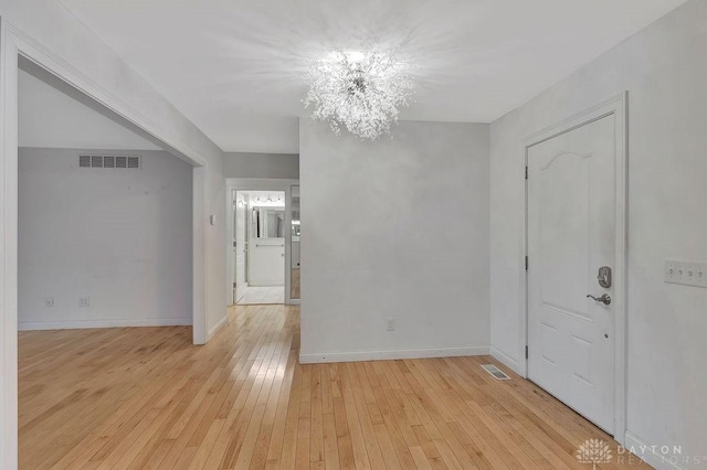 unfurnished room featuring light hardwood / wood-style flooring and a notable chandelier