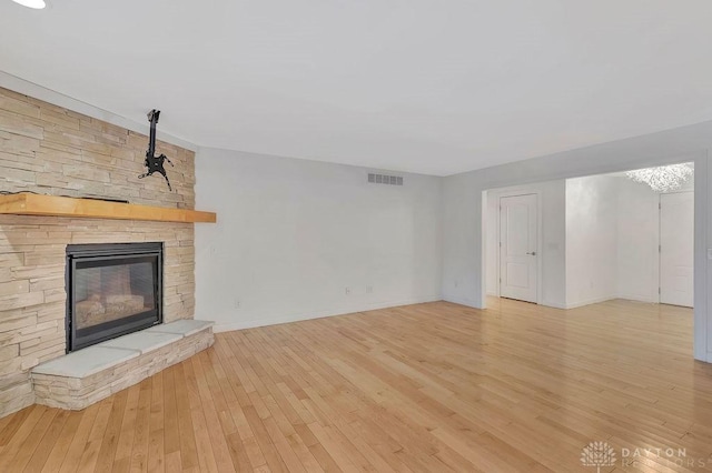 unfurnished living room with a stone fireplace and light hardwood / wood-style floors