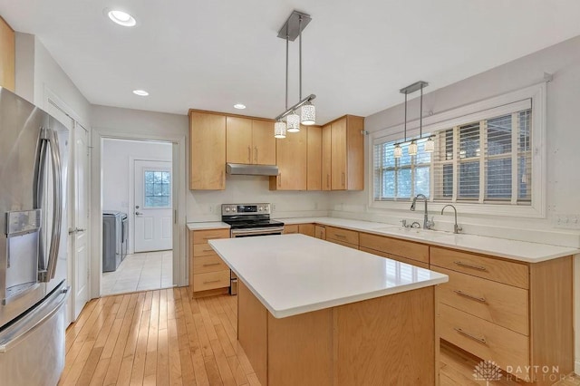 kitchen featuring sink, appliances with stainless steel finishes, a kitchen island, separate washer and dryer, and decorative light fixtures