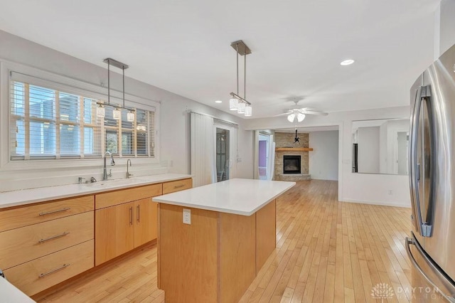 kitchen featuring sink, decorative light fixtures, stainless steel refrigerator, and a center island