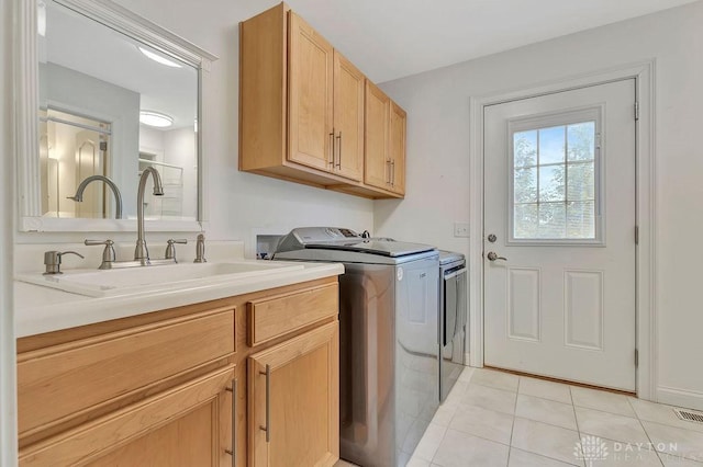 laundry room featuring light tile patterned flooring, cabinets, washer and clothes dryer, and sink