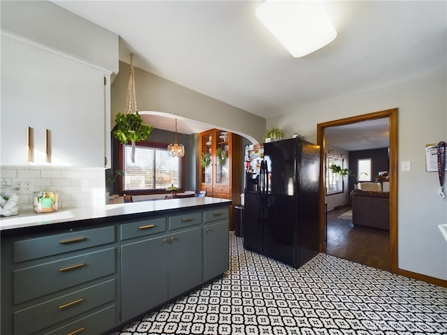 kitchen with backsplash, black fridge with ice dispenser, and a chandelier