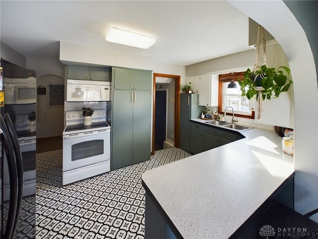 kitchen with sink, white appliances, white cabinetry, backsplash, and kitchen peninsula