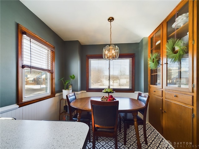 dining room featuring wooden walls and a chandelier