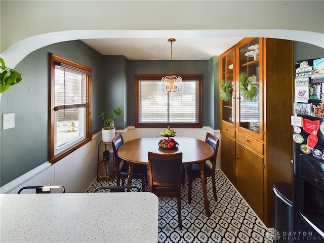 dining space with an inviting chandelier and wooden walls