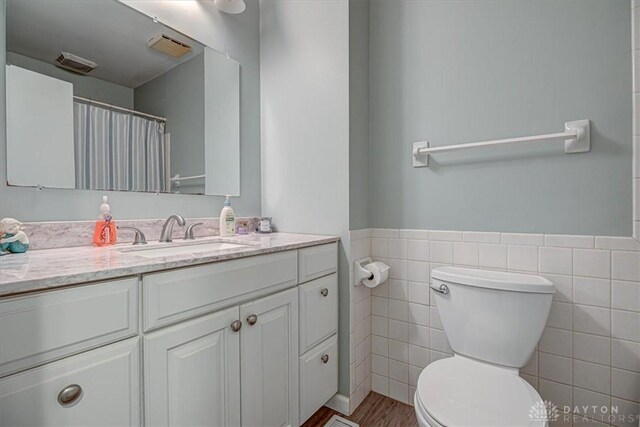 bathroom with vanity, tile walls, and toilet