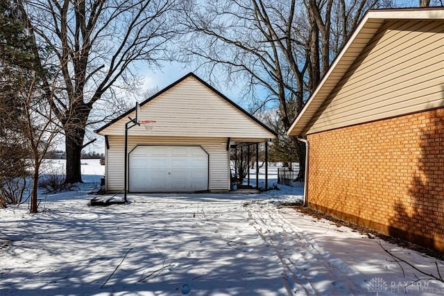 view of snow covered exterior featuring a garage and an outdoor structure