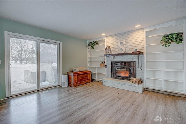 unfurnished living room featuring a fireplace, built in features, a textured ceiling, and light wood-type flooring