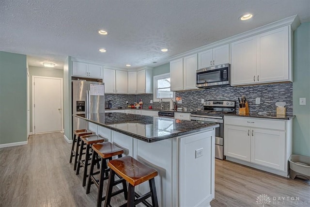 kitchen featuring stainless steel appliances, a kitchen island, and white cabinets