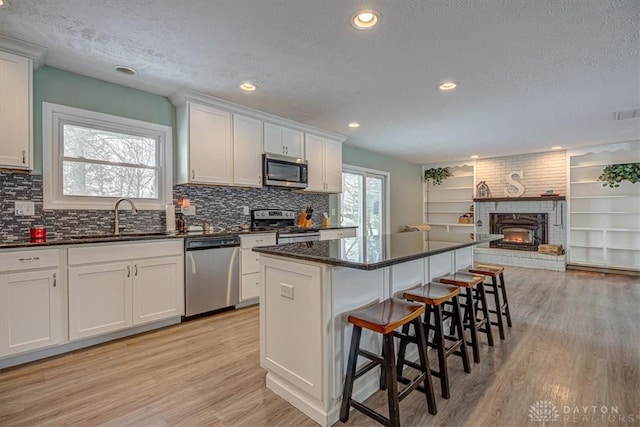 kitchen featuring sink, stainless steel appliances, white cabinets, and a kitchen island