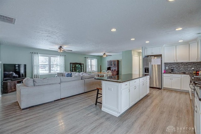 kitchen featuring stainless steel fridge, a kitchen breakfast bar, white cabinets, and a kitchen island